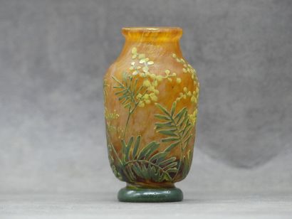 null DAUM. Petit vase en verre orangé à décor de mimosa vert. Piédouche et col évasé....