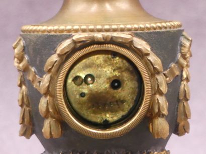 null Petite horloge en bronze patiné et doré figurant une urne à décor de guirlandes....
