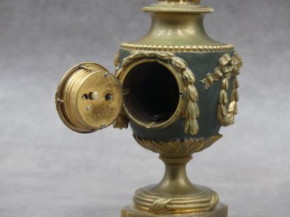 null Petite horloge en bronze patiné et doré figurant une urne à décor de guirlandes....