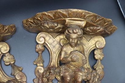 null Pair of carved and gilded wood consoles decorated with putti and cymbals. Regency...