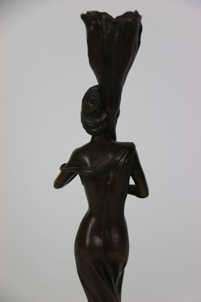 null Grand bougeoir en bronze figurant une jeune femme en robe portant une tulipe....