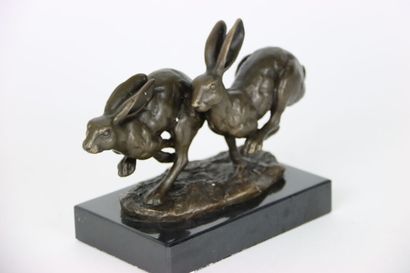 null Bronze figurant deux lièvres en fuite courant côte à côte, sur une base en marbre....