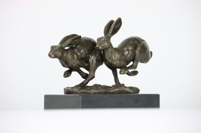 null Bronze figurant deux lièvres en fuite courant côte à côte, sur une base en marbre....