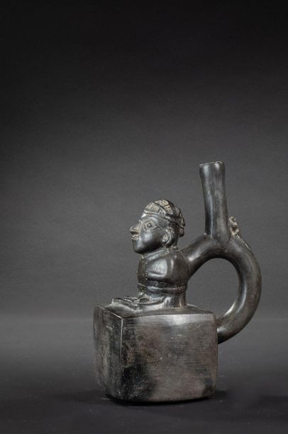 null Vase with a stirrup-shaped handle in the shape of a cube 

A figure sitting...
