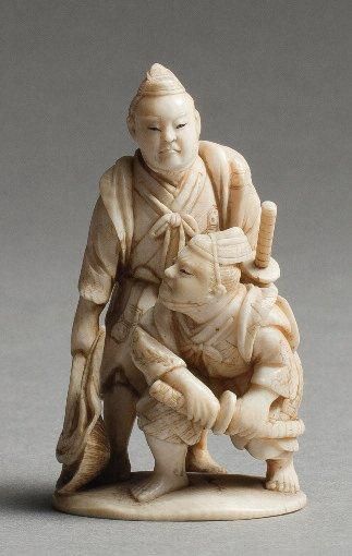 null NETSUKE en ivoire à patine jaune représentant deux samourais avec leurs attributs...