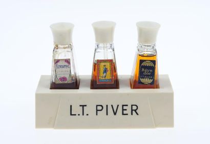 L.T. PIVER Présentoir en bakélite blanche comprenant trois flacons en verre, bouchons...