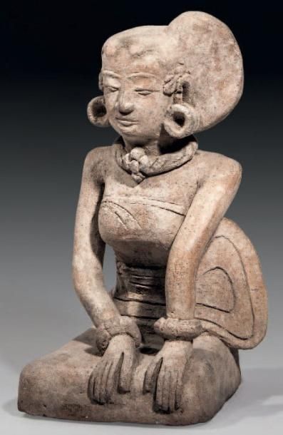 null STATUETTE DE FEMME EN TERRE CUITE. Assise, les mains posées sur sa robe laissant...