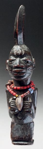 null STATUETTE ESHU agenouillée, les bras repliés sur la poitrine et tenant dans...