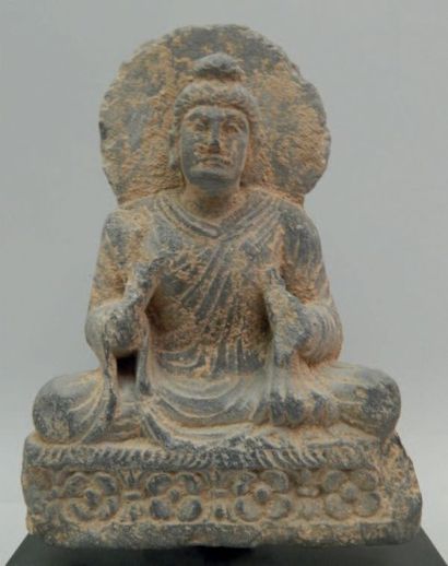 Bouddha assis sur un trône orné de corolles....