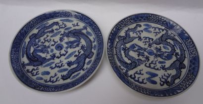 null Deux soucoupes en porcelaine à décor en camaieu bleu de deux dragons affrontés,...