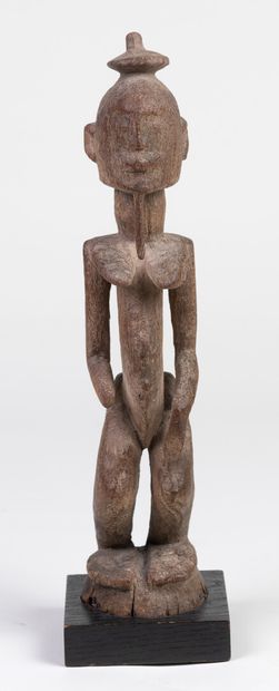 null Statuette carved with a figure standing on a circular base, hands on the lower...