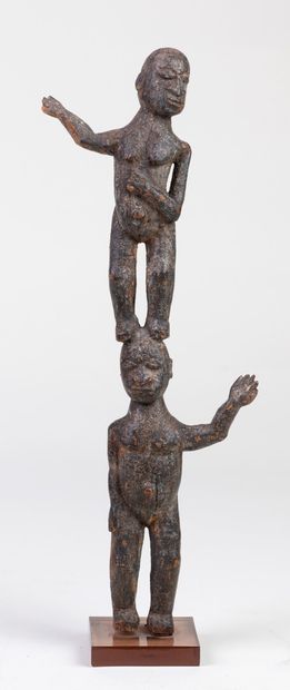 null Statuette carved with two characters, one female placed on the head of the other...