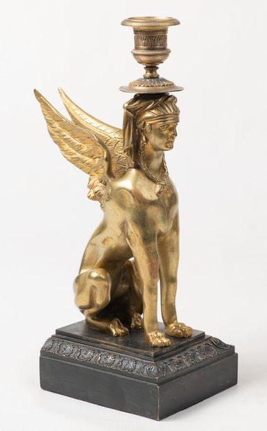 null a gilt bronze candlestick decorated with a winged sphinx on its base, rubbing...