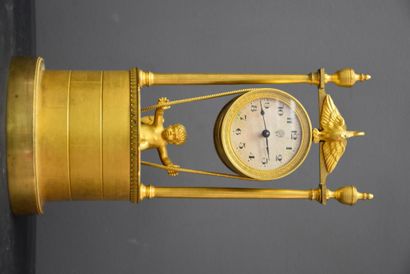 A clock with a cherub swinging above the...