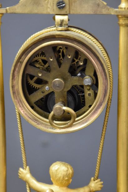 null 一个时钟，上面有一个小天使在井上摇摆。鎏金青铜，帝国时期。报告的机制。高度：22.5厘米。