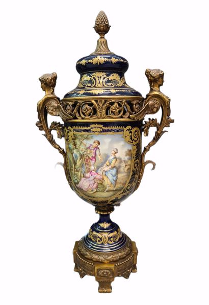 null 令人印象深刻的塞夫勒风格的法国瓷器套装，带有丰富的青铜器装饰。拿破仑三世风格，19世纪末/约1900年。这套作品包括一对大的有盖花瓶和一个中央的花瓶。蓝底的瓷器上有鎏金的珐琅，并以储备的方式装饰着浪漫的场景，前面有L....