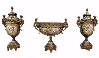 令人印象深刻的塞夫勒风格的法国瓷器套装，带有丰富的青铜器装饰。拿破仑三世风格，19世纪末/约1900年。这套作品包括一对大的有盖花瓶和一个中央的花瓶。蓝底的瓷器上有鎏金的珐琅，并以储备的方式装饰着浪漫的场景，前面有L....