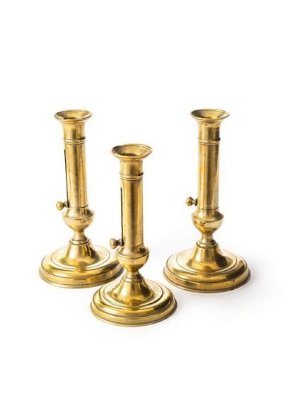 null Suite of three brass night candlesticks, the baluster shaft with a frieze of...