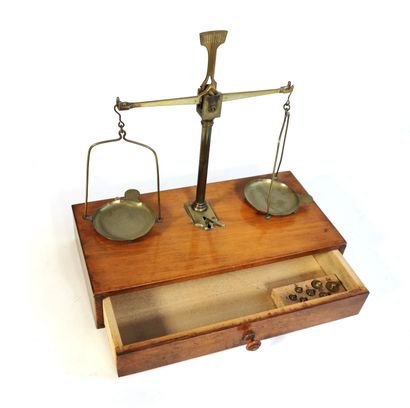 null A precision scale in brass and natural patinated wood with weights from 1 to...