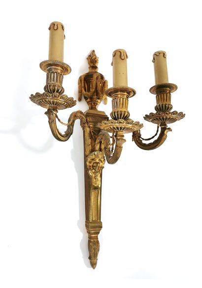 null A three-light gilt bronze wall lamp with gadrooned wicks and a mascaron shaft...