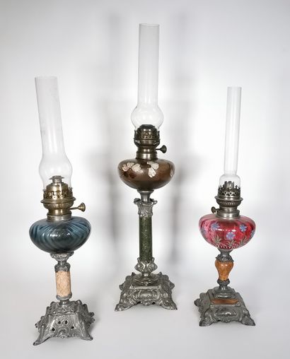 null Suite of three oil lamps in brass, stamped metal, composite marble and enamelled...
