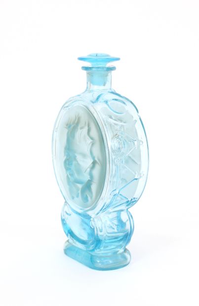 null Bottle out of blown and moulded glass tinted blue with decoration of the heads...