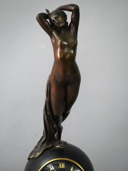 null PENDULE en bronze à patine brune et dorée, le mouvement surmonté d'une sculpture...