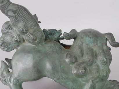 null ASIA, 20th century. Dog of Fô in movement holding a peony in its mouth. Bronze...
