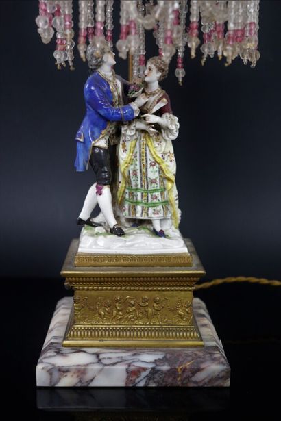 null Brass and marble lamp, including a polychrome porcelain group and topped with...