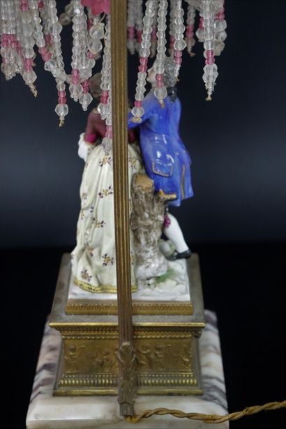 null Brass and marble lamp, including a polychrome porcelain group and topped with...