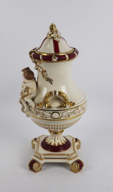null Vase couvert en porcelaine à décor de deux amours tenant une guirlande, surmontant...