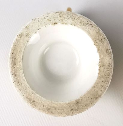 null PARIS.

Tasse ovoïde à anse élevée et sa sous-tasse en porcelaine à décor polychrome...