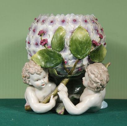 null Cache-pot en porcelaine polychrome représentant deux putti soulevant une fleur
H...