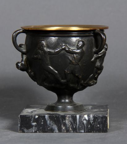 null A black patina bronze bowl with three handles decorated with a wrestling scene....