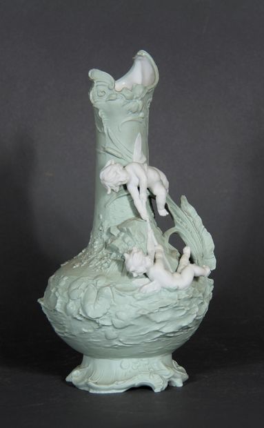 null A light green painted biscuit vase on a foot with a relief decoration of loves...