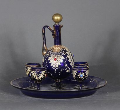 null A dark blue transparent glass liquor set with white enamelled scroll decoration...