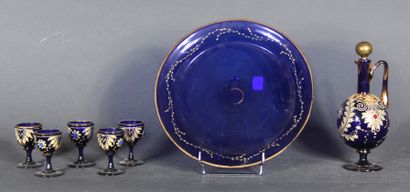 null A dark blue transparent glass liquor set with white enamelled scroll decoration...