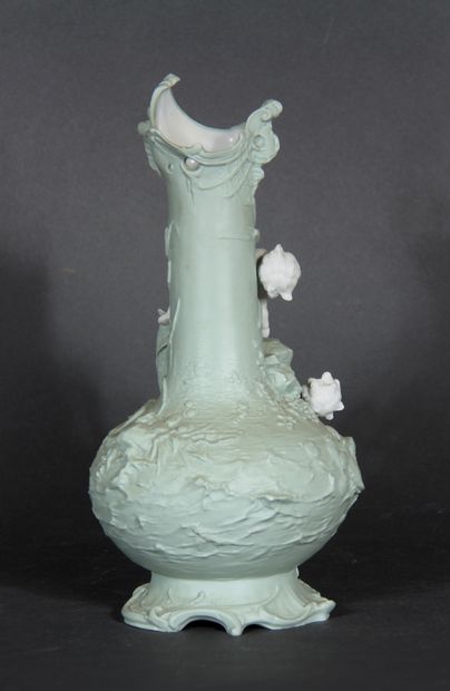null A light green painted biscuit vase on a foot with a relief decoration of loves...