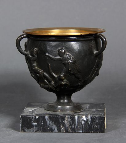 null A black patina bronze bowl with three handles decorated with a wrestling scene....