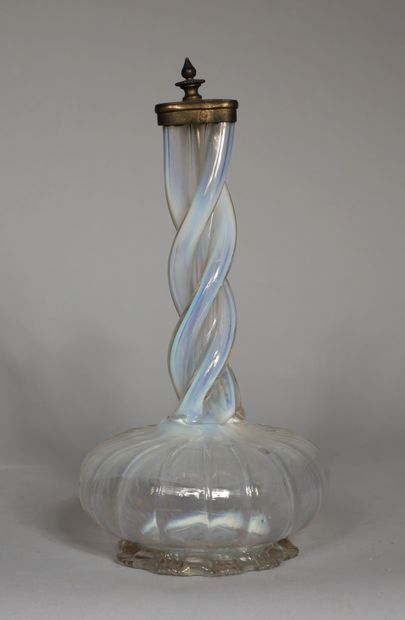 null A transparent, slightly iridescent glass vase on a heel with a flattened body,...