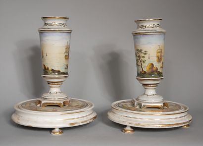 null A pair of white and gilt porcelain vases on a pedestal decorated with a polychrome...