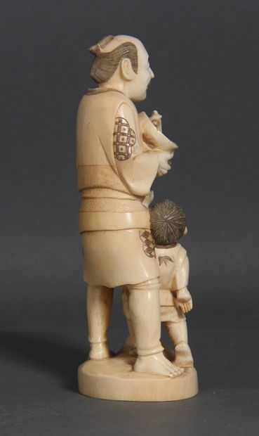 null Okimono en ivoire et rehauts bruns, représentant un paysan et un enfant, le...