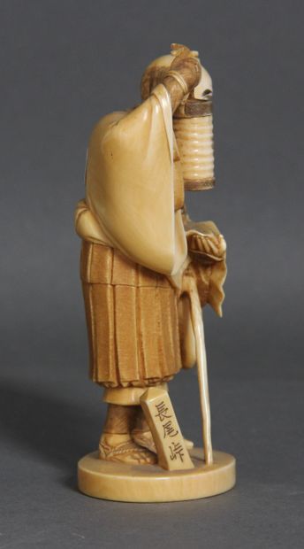 null Okimono en ivoire et rehauts bruns, représentant un moine levant une lanterne...