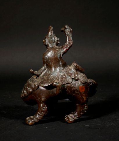 null *Sculpture en métal patiné en forme d'un personnage sur un chien de Fô, Chine

H...