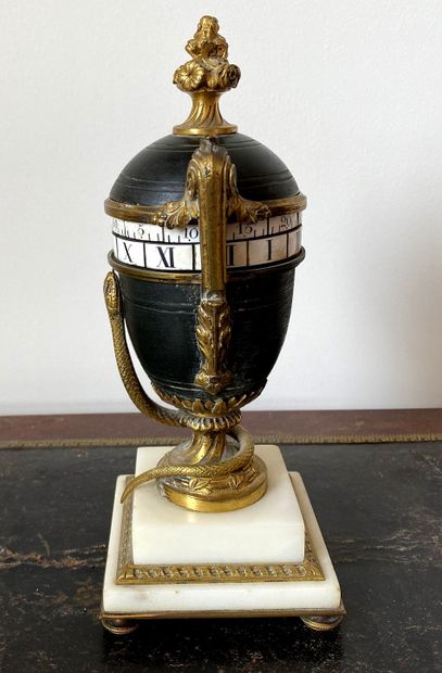 null Antique vase-shaped rotating clock on pedestal and snake in patinated metal,...