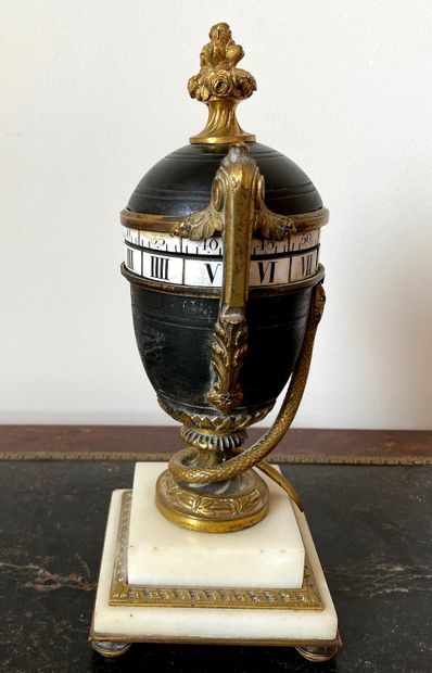 null Antique vase-shaped rotating clock on pedestal and snake in patinated metal,...