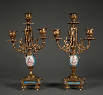 null A pair of bronze and porcelain candelabras decorated with putti and bouquets...