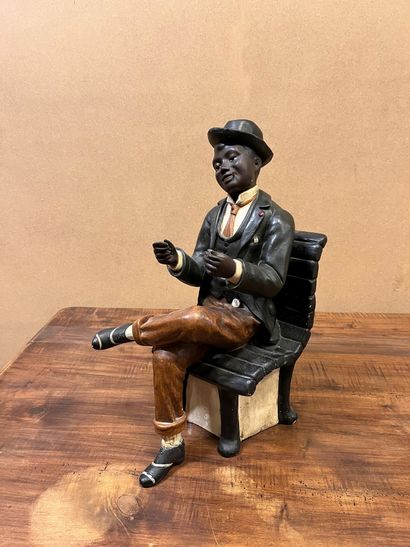 null Sculpture en plâtre polychrome représentant un jeune noir assis, à la cigarette...