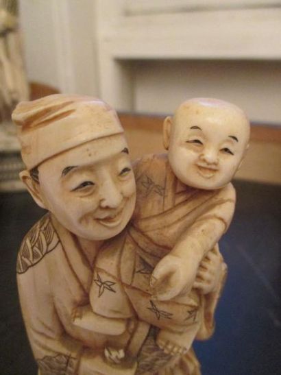 null Okimono en ivoire représentant un homme tenant dans ses bras un enfant.
Japon,...