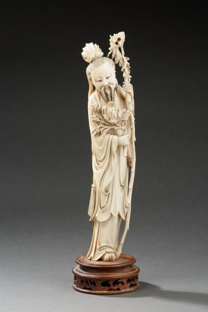 null Statuette en ivoire représentant un sage tenant une branche de pivoines en fleurs....
